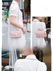 Pink mini crossbody bag with crocodile texture and pearl buckle detail shown on model