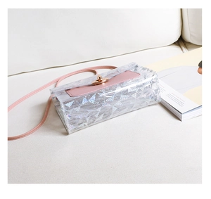 Detail of pink leather flap and golden twist lock on transparent geometric PVC handbag