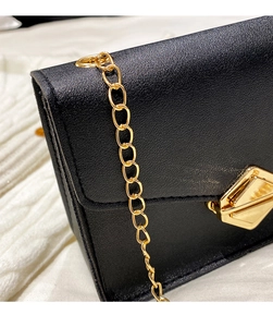 Close-up of black lychee grain leather mini square bag with golden geometric clasp
