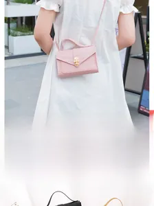 Detailed close-up of pink mini crossbody bag with crocodile texture and pearl buckle