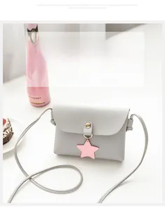 Detail of grey mini square bag with pink star charm and gold magnetic snap closure