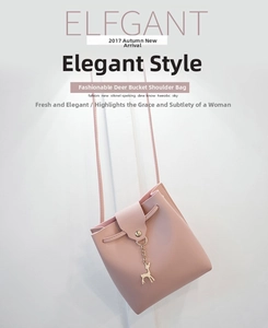 Pink minimalist bucket bag with a golden deer charm hanging against a white wall