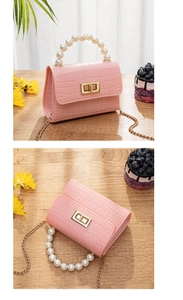 Detailed view of pink croc-effect mini bag with pearl handle on a wooden table