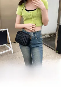 Quilted black leather camera bag with gold chain strap shown on a fashion model