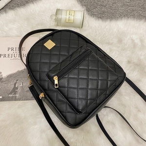 Chic black quilted backpack with gold hardware and front pocket on plush white carpet