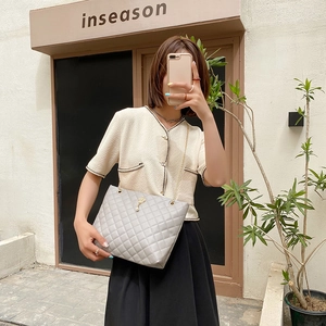 Light gray quilted tote bag with gold chain strap and pearl crown charm in street style