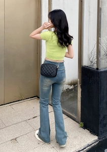 Outdoor street style view of a black quilted chain bag paired with a green knit top