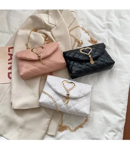Detail of quilted chain crossbody bags with heart-shaped gold buckles and tassel charms