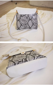 Detail of snake print flap and white base on a luxury synthetic leather crossbody bag