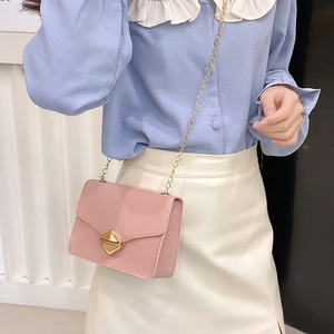 Pink mini crossbody chain bag with gold diamond clasp shown on model wearing a skirt