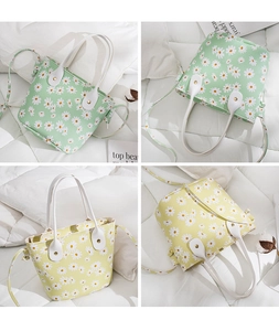 Detail view of small daisy print tote bags in mint green and yellow with white handles