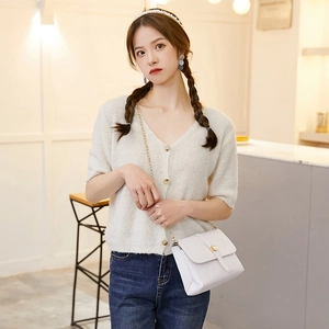 Minimalist white leather crossbody bag with gold chain strap shown on a model