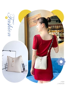 Detail of white crocodile pattern bucket bag with LOVE printed wide shoulder strap