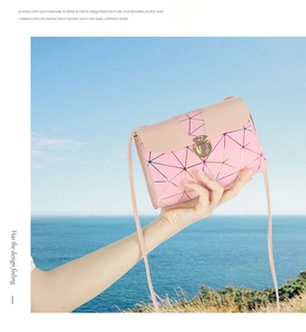 Pink crossbody bag with geometric triangle patterns and gold rotating twist hardware detail