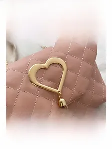 Close-up of pink quilted bag featuring a golden heart lock and metallic tassel details