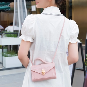 Pink crocodile pattern mini handbag with pearl metal lock shown on a female model
