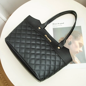 Classic black quilted tote bag with gold hardware and embroidery on a white surface