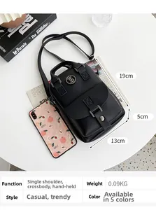Detail of black pebbled leather crossbody phone bag with metal logo on white desk