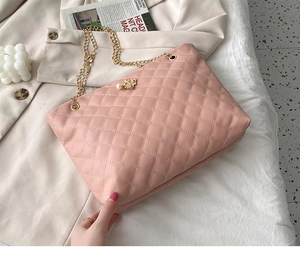 Detail der rosa gesteppten Beuteltasche mit Kronen-Perlenanhänger und Goldkette