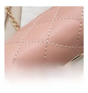 Detailed macro view of firm stitching and litchi grain texture on pink crossbody bag