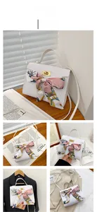 Detail of white crocodile pattern Kelly bag with floral silk scarf and gold twist lock