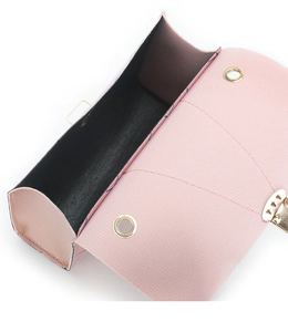Detail of pink crossbody bag with gold floral buckle and black velvet interior lining