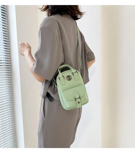 Detail view of mint green crossbody bag with TB logo and top handle worn by a model