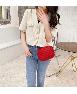 Close-up of red quilted faux leather crossbody bag with elegant gold chain strap detail