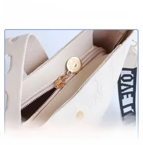Detail of white crocodile embossed bag with gold anti-theft lock and LOVE strap