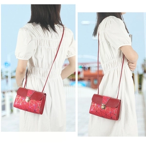 Detail of burgundy geometric shoulder bag featuring a metallic clasp and leather strap