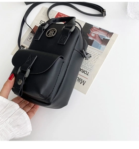 Detail of black pebbled leather crossbody bag with metal TB logo and adjustable strap