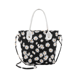 Chic black bucket bag with daisy print, featuring white handles and detachable strap