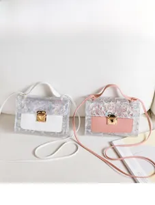 Detail of holographic geometric PVC crossbody bags in white and pink on a white sofa