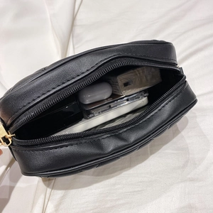 Black quilted crossbody camera bag with gold zipper showing spacious inner storage