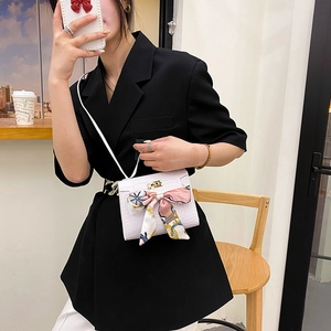 White crocodile pattern crossbody bag with silk scarf bow and gold clasp shown on model