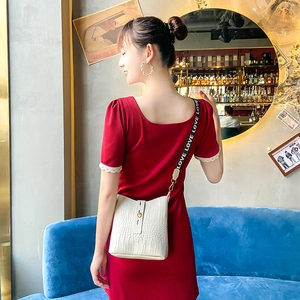White faux-crocodile pattern bucket bag with wide 'LOVE' printed shoulder strap