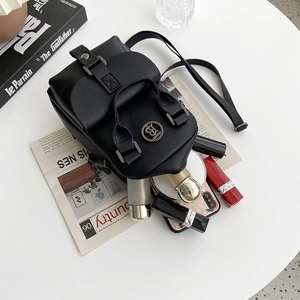 Fashionable black lychee leather crossbody bag with items inside on a white desk