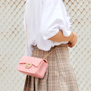 Sac bandoulière rose en silicone matelassé avec chaîne dorée porté par un mannequin