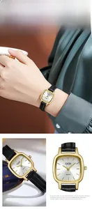 Detail of elegant gold square quartz watch with black leather strap on female wrist