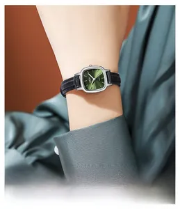 Close-up of minimalist emerald green square watch with black leather strap on wrist