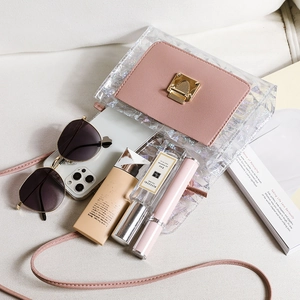 Transparent laser crossbody bag with pink flap and gold buckle on a lifestyle background