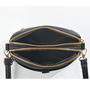 Internal view of black leather crossbody bag featuring three golden zip compartments