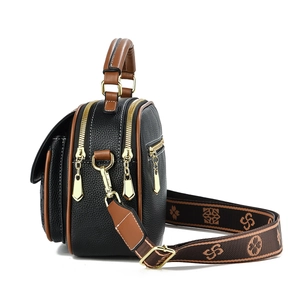Detail of black and brown leather handbag featuring golden zippers and floral strap