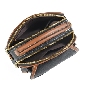 Macro view of three zipper compartments on black and brown leather handbag with gold hardware