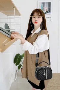 Close-up of black quilted shoulder bag with bear charm and geometric wide strap