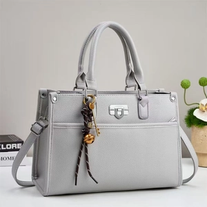 Détail du sac à main gris en cuir texturé avec des breloques décoratives