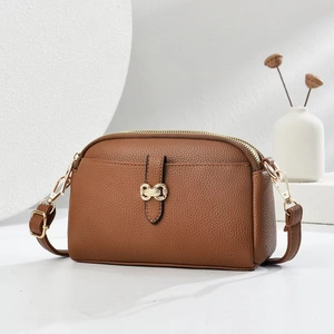 Close-up of brown litchi pattern leather bag with gold double-ring hardware detail