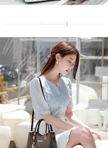 Outdoor model display of a stylish brown patterned tote bag with golden twist lock