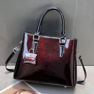 Macro detail of glossy snakeskin textured dark red faux leather handbag with silver hardware