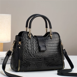 Detailed macro view of the crocodile pattern leather and gold hardware on black tote bag